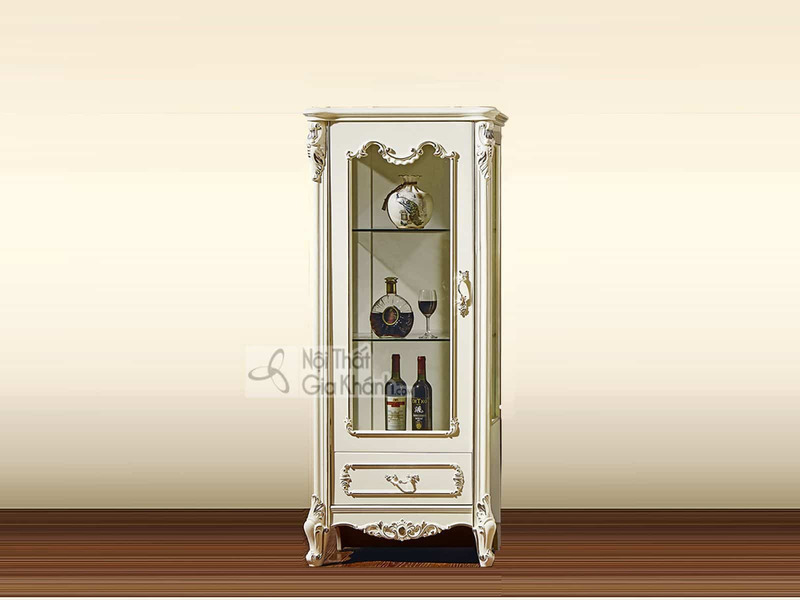 Tủ rượu 1 cánh TR8801H-1 phong cách tân cổ điển, màu trắng kem, được chụp chính diện trên nền tường màu be nhạt và sàn gỗ…
