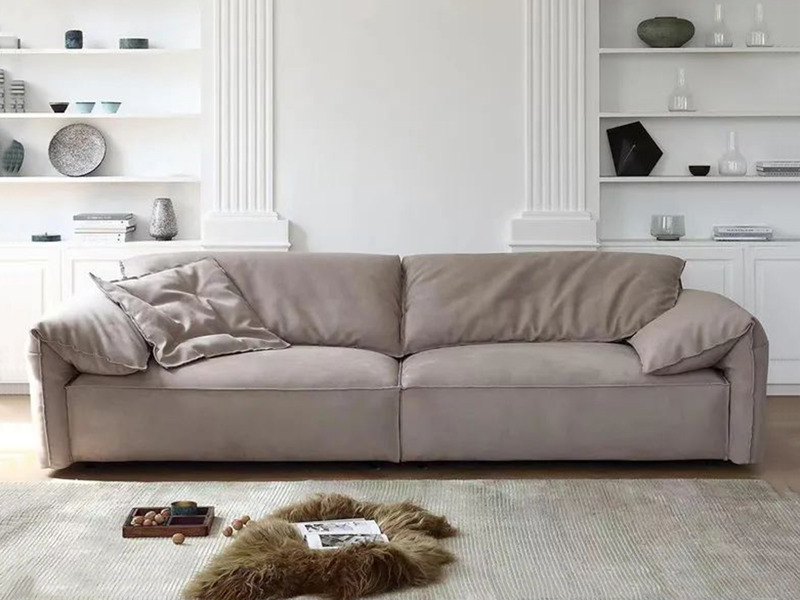 Sofa băng ba chỗ ngồi màu nâu be nhạt, đặt chính diện trong phòng khách hiện đại. Ghế có kiểu dáng tối giản, đệm ngồi và t…