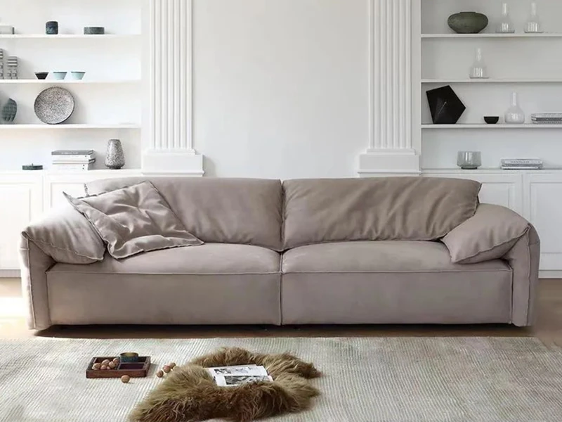 Sofa băng ba chỗ ngồi màu nâu be nhạt, đặt chính diện trong phòng khách hiện đại. Ghế có kiểu dáng tối giản, đệm ngồi và t…