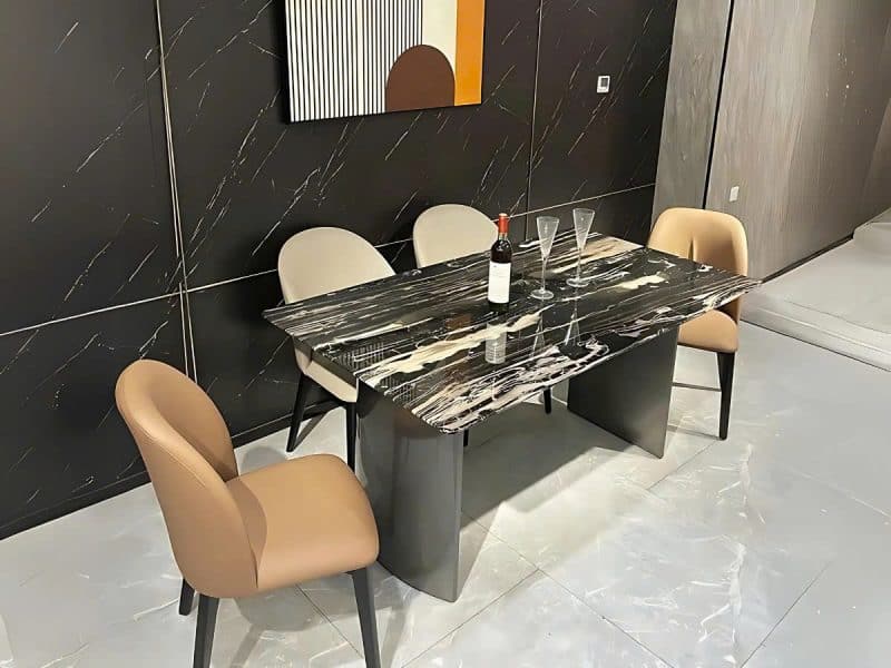 Bàn ăn 1m6 mặt đá BA6385 phong cách hiện đại, chụp từ góc hơi chếch, nổi bật mặt đá hoa băng đen nhân tạo với vân trắng và…