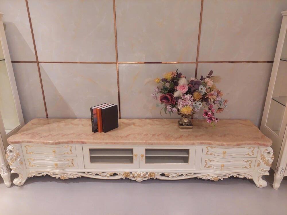 Hình ảnh tổng thể kệ tivi KT622-24 phong cách tân cổ điển, màu trắng ngọc trai kết hợp họa tiết mạ vàng nổi bật. Kệ có mặ…