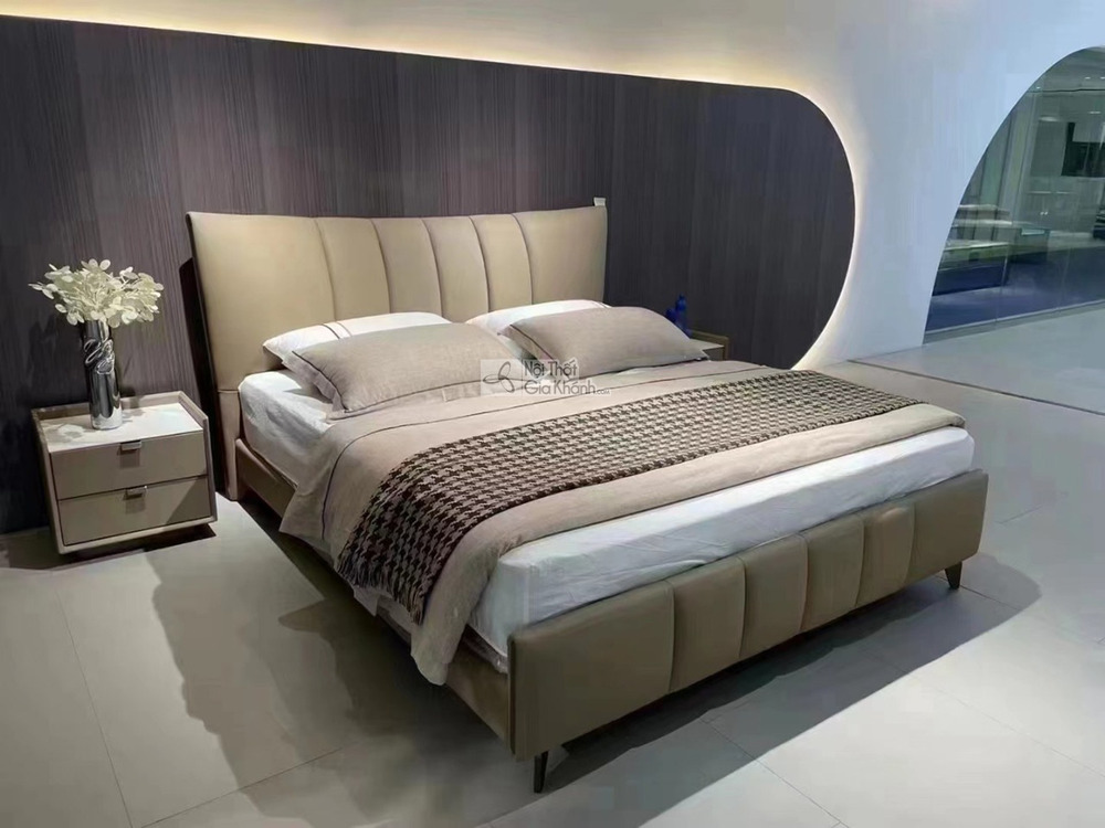 Giường ngủ bọc da hiện đại GIBJ108-18 chụp góc chếch, nổi bật đầu giường cao bọc da nâu be với đường may dọc. Khung giường…