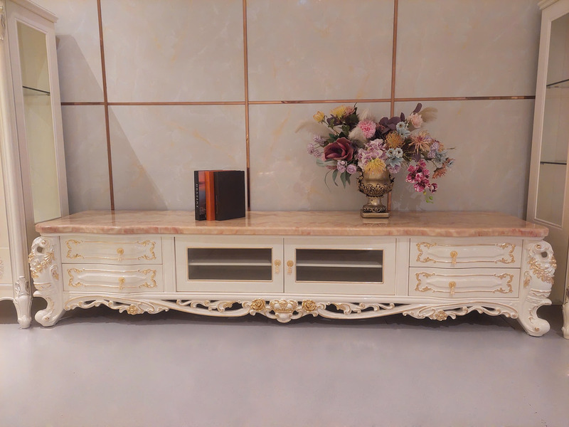 Kệ tivi tân cổ điển KT622-24 màu trắng ngọc trai với mặt đá hồng ngọc long nhân tạo, được chụp chính diện trong không gian…