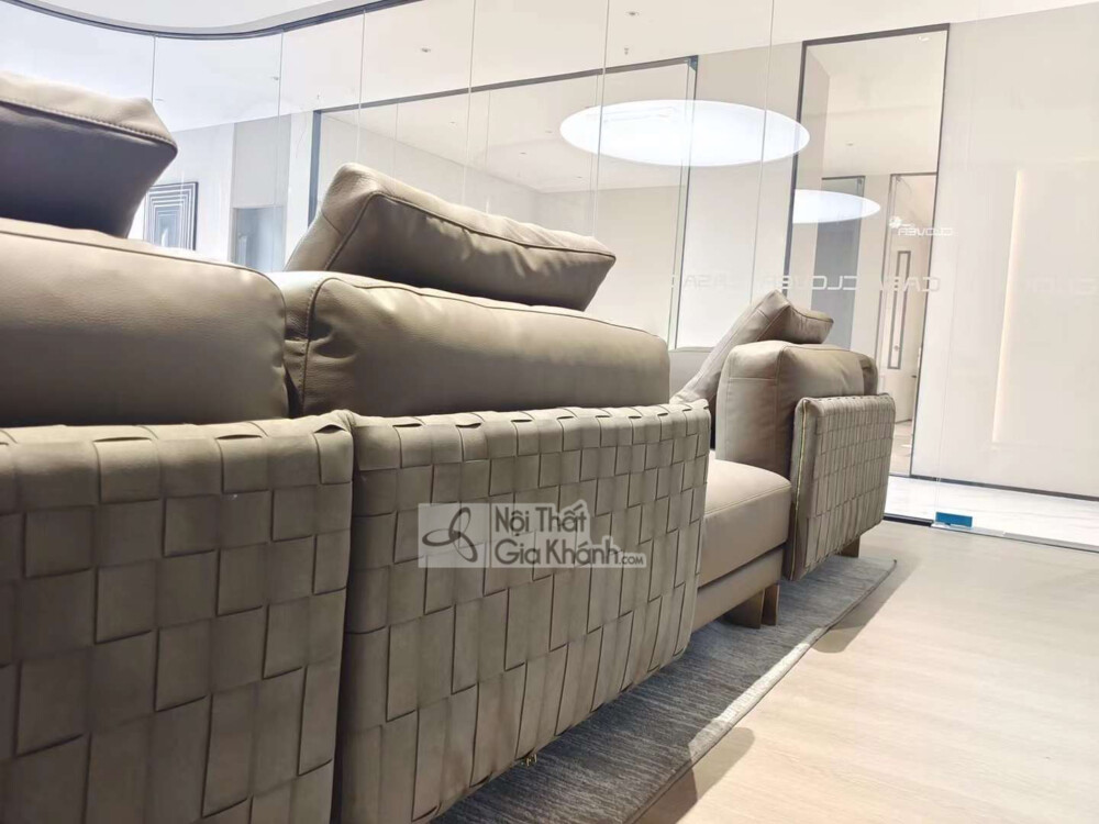 Góc chụp cận cảnh phần lưng và tay vịn của bộ sofa góc phải, bọc da màu nâu xám. Tay vịn nổi bật với chi tiết đan lưới độc…