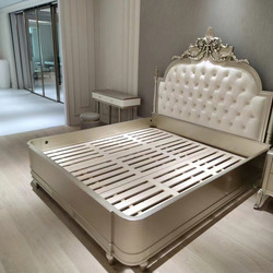 Giường ngủ 1m8 phong cách tân cổ điển, chụp từ góc chếch. Đầu giường bọc da nhân tạo màu kem, chần nút, kết hợp chạm khắc…