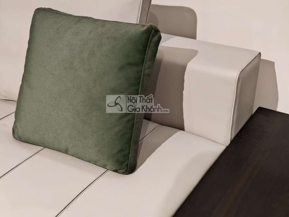 Cận cảnh phần góc của bộ sofa SF2201-2, nổi bật với gối tựa màu xanh rêu đặt trên nền da màu kem nhạt. Đường may tinh tế c…