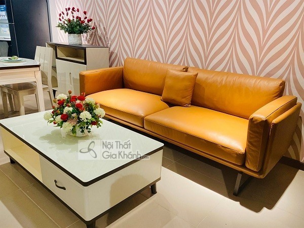 Ghế sofa nệm bọc da màu cam đất dáng băng dài đặt cạnh bàn trà trắng