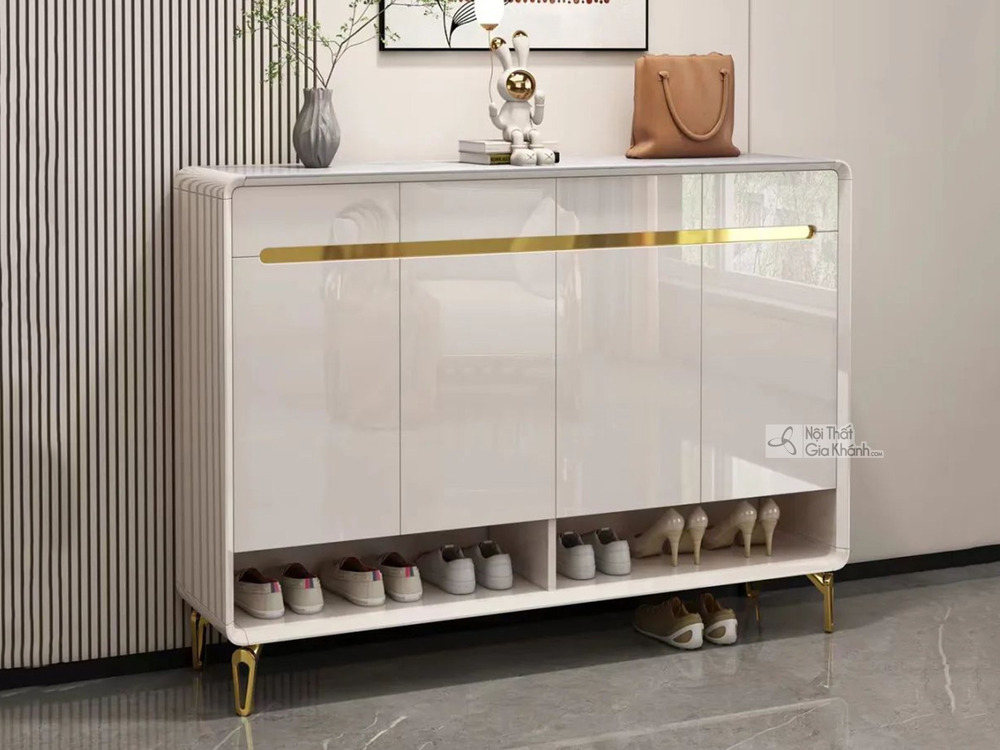Tủ giày TDB504 màu trắng bóng, phong cách hiện đại, đặt trong không gian tiền sảnh. Tủ có mặt trên bằng đá vân xám, ba cán…