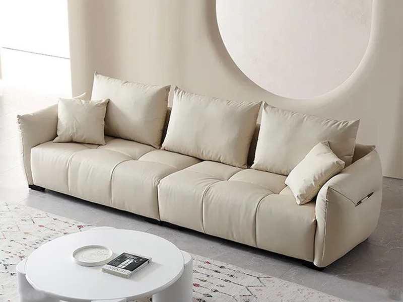 Sofa băng SFA09-4 màu kem nhạt, chụp từ góc hơi chếch phía trước, đặt trong không gian phòng khách hiện đại. Sofa có thiết…