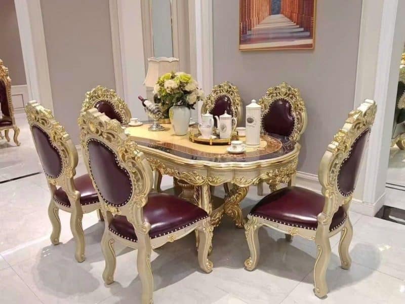 Bộ bàn ăn tân cổ điển gồm bàn hình oval và sáu ghế, chụp từ góc hơi chếch, tập trung vào chi tiết tinh xảo của khung bàn v…