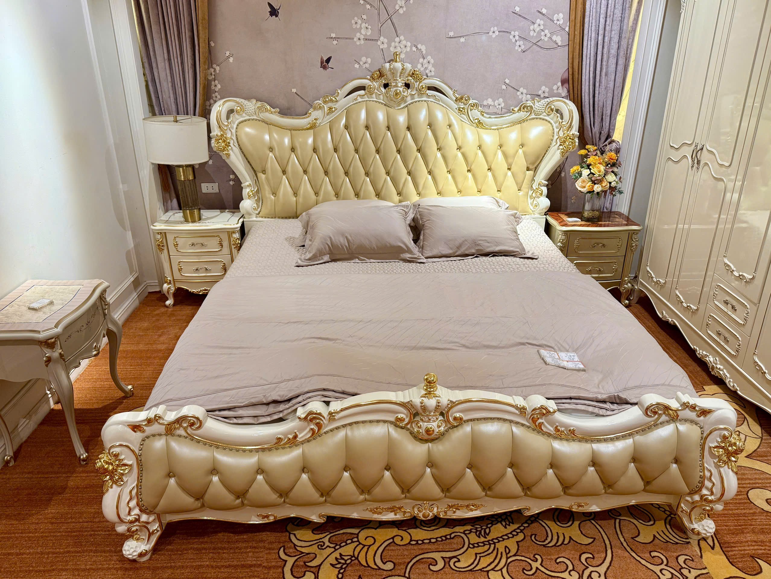 Giường ngủ tân cổ điển GIB68-20 màu trắng ngọc trai được chụp từ góc nghiêng bên trái, đặt trong phòng ngủ với tường họa t…