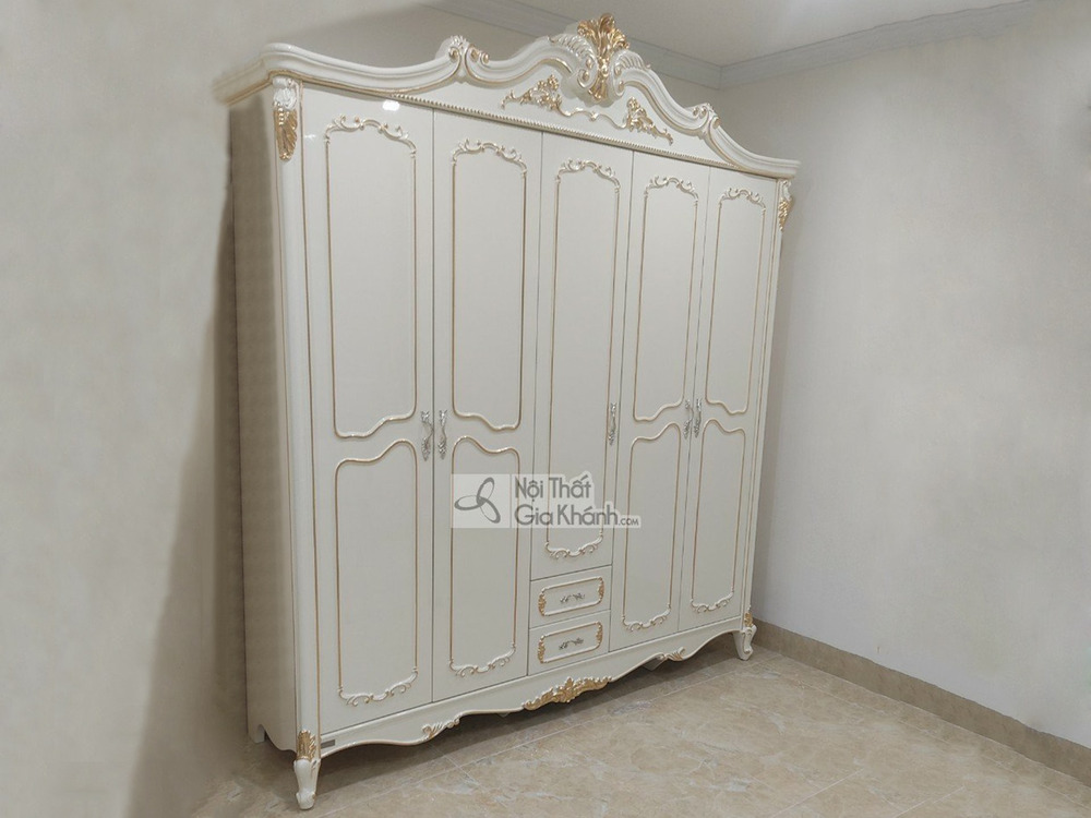 Tủ quần áo 5 cánh TU8803H dát vàng họa tiết được chụp chính diện trong một căn phòng trống với tường trắng và sàn gạch màu…