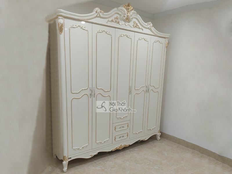 Tủ quần áo 5 cánh TU8803H dát vàng họa tiết được chụp chính diện trong một căn phòng trống với tường trắng và sàn gạch màu…