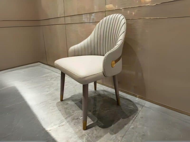 Ghế ăn cao cấp QY30 chụp từ góc chếch, thể hiện kiểu dáng hiện đại luxury. Ghế bọc da nhân tạo cao cấp màu kem nhạt, lưng…