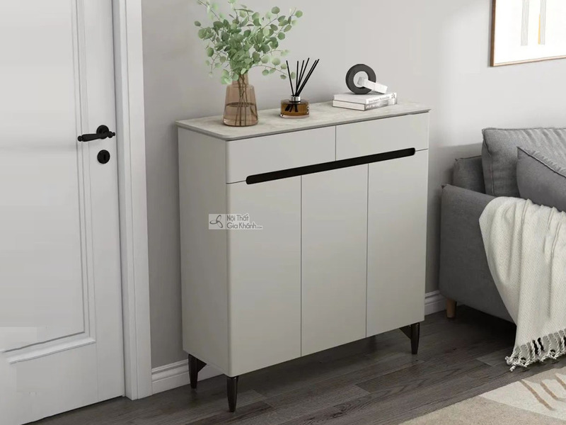 Tủ giày hiện đại TDA-100 màu xám nhạt, mặt trên vân đá sáng, được đặt gọn gàng cạnh cửa ra vào và một chiếc ghế sofa màu x…