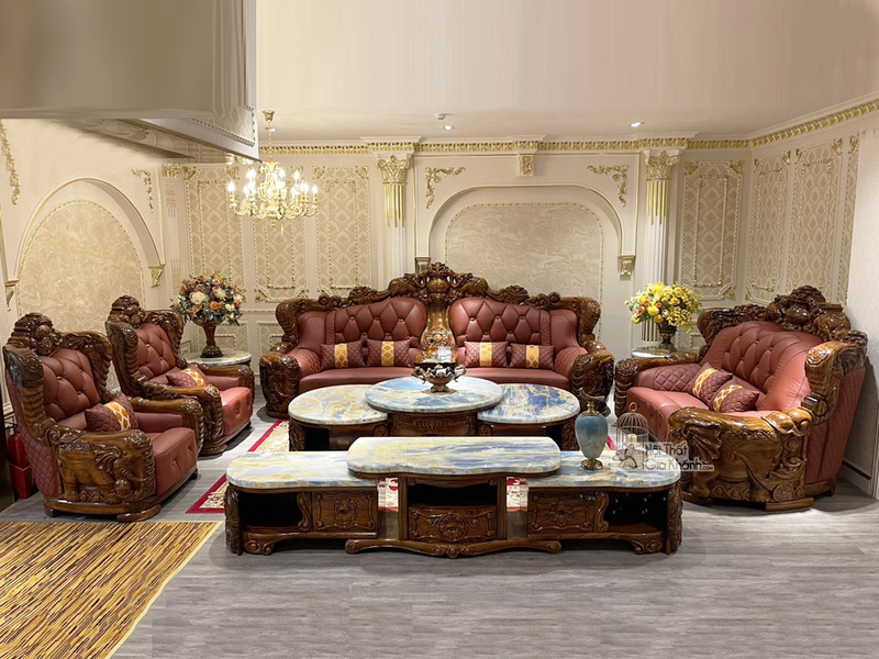 Toàn cảnh bộ sofa gỗ Mun tân cổ điển trong phòng khách sang trọng, góc chụp rộng từ phía trước. Các băng ghế và ghế đơn bọ…