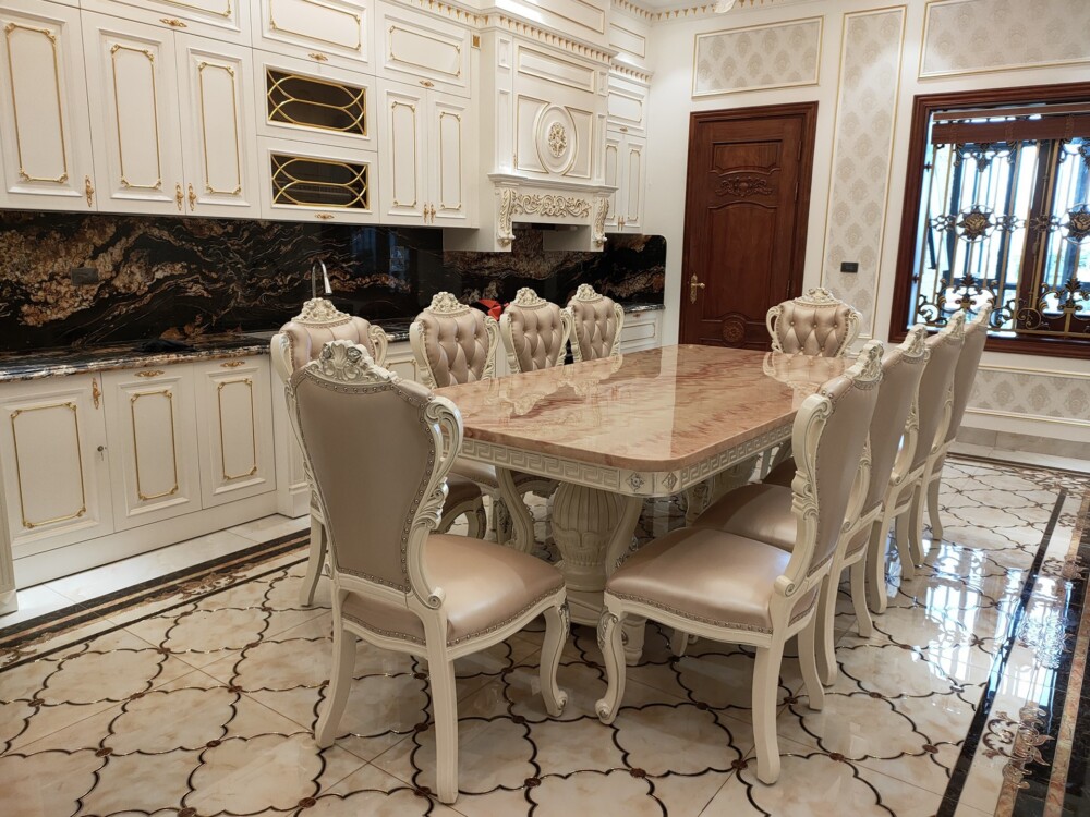 Bộ bàn ăn tân cổ điển 10 ghế, chụp từ phía sau, cho thấy rõ lưng ghế bọc da màu kem nhạt với đường cong mềm mại và các chi…