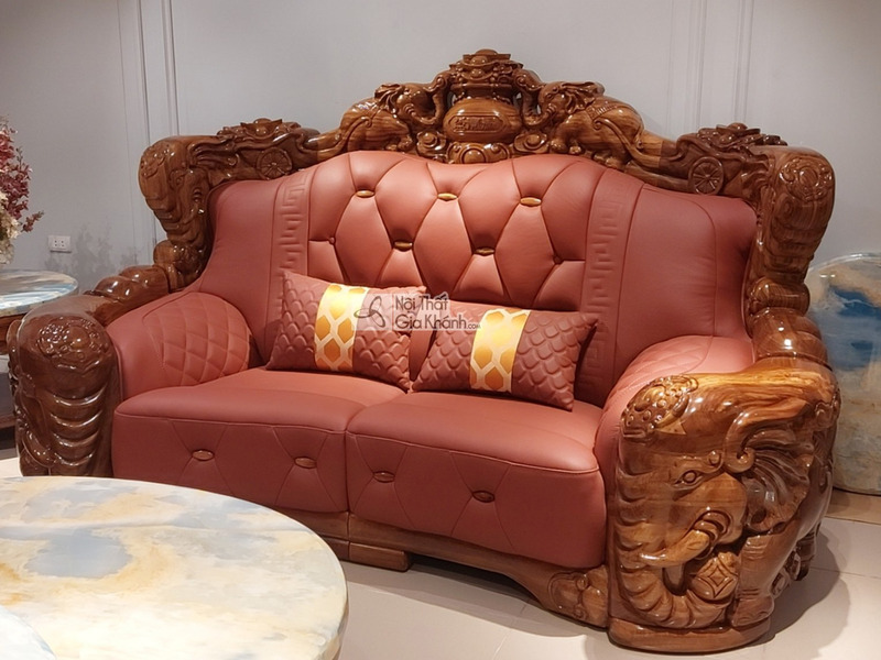 Cận cảnh băng sofa hai chỗ ngồi màu nâu đỏ, bọc da bò tót cao cấp, với khung gỗ mun Nam Phi được chạm khắc hoa văn cầu kỳ…