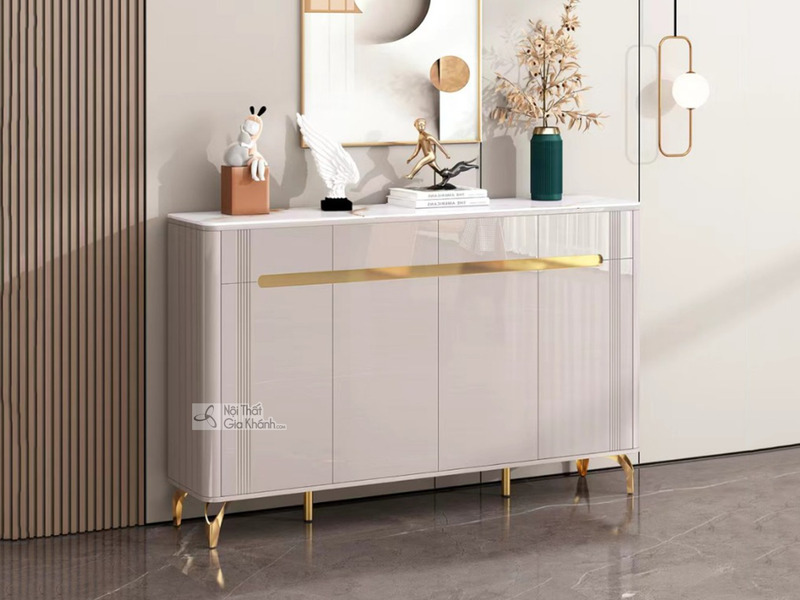 Tủ giày hiện đại TDEH168 được chụp chính diện, nổi bật với tông màu trắng kem bóng sang trọng. Mặt trên của tủ ốp đá vân t…