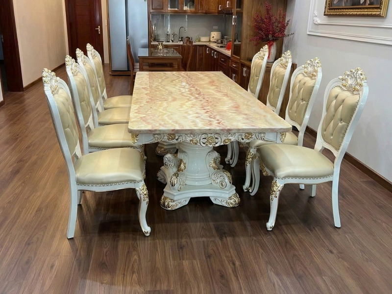 Bộ bàn ăn 10 ghế BAT66-24 chụp cận cảnh từ phía trước, đặt trên sàn gỗ. Bàn ăn mặt đá Hồng ngọc long nhân tạo với vân đá đ…