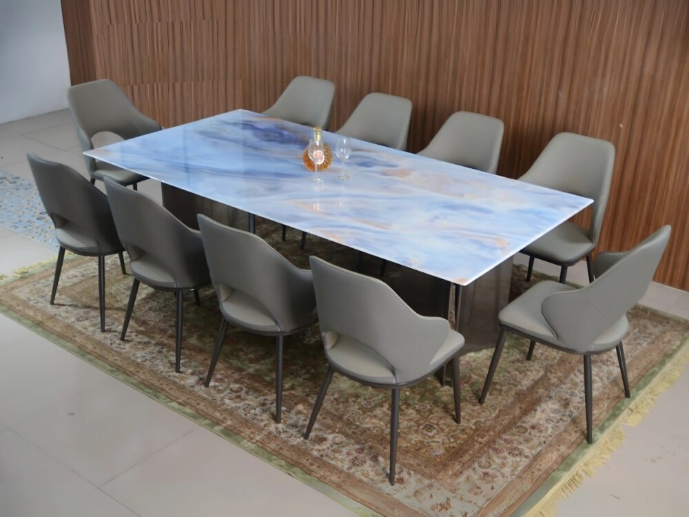 Bộ bàn ăn 10-12 người BAQ55-24 nhìn từ góc chéo, với mặt đá pha lê nhân tạo màu xanh vân mây và chân thép không gỉ màu xám…