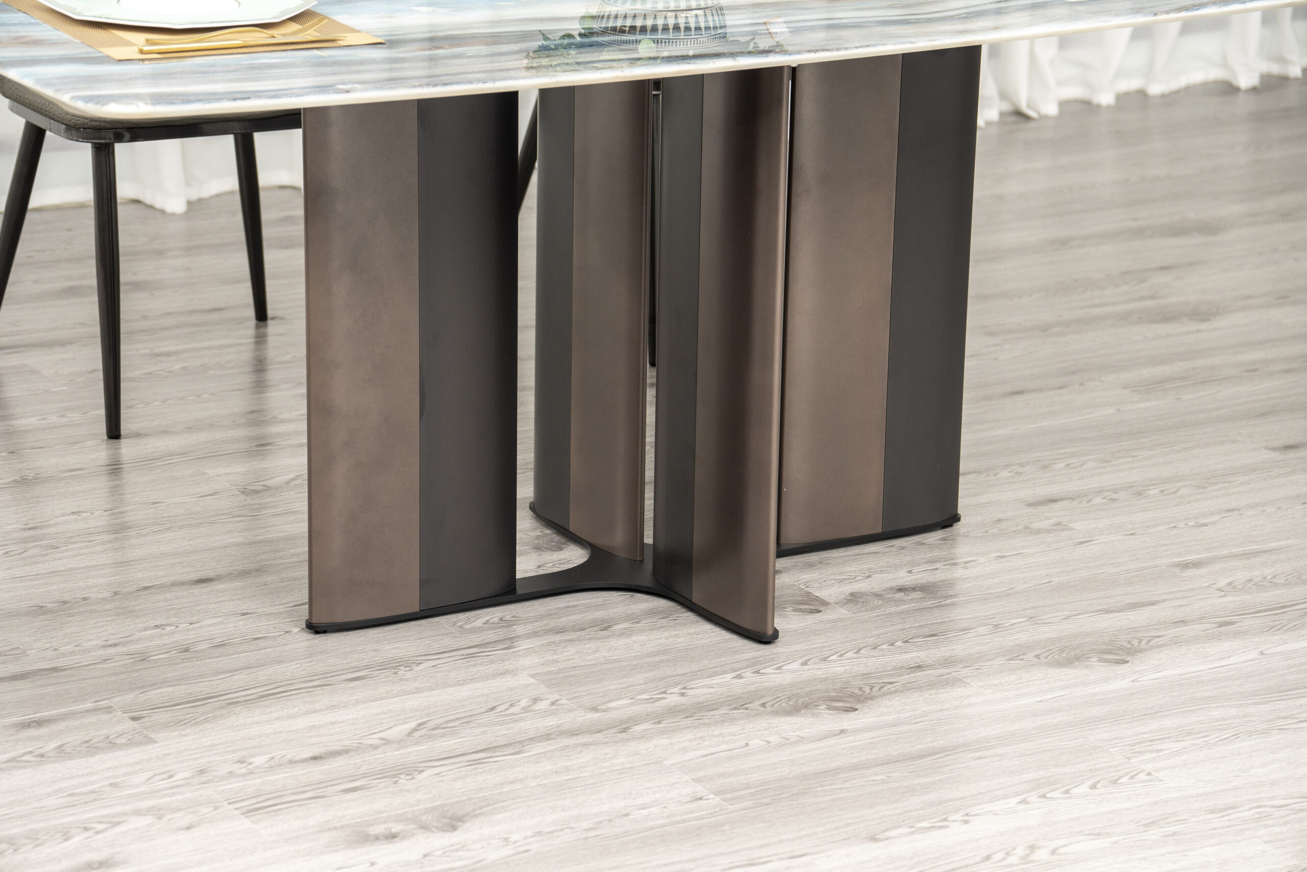 Cận cảnh chân bàn ăn BA934 với thiết kế hình cánh hoa độc đáo, làm từ thép không gỉ màu nâu sẫm, mang lại sự vững chắc. Mặ…