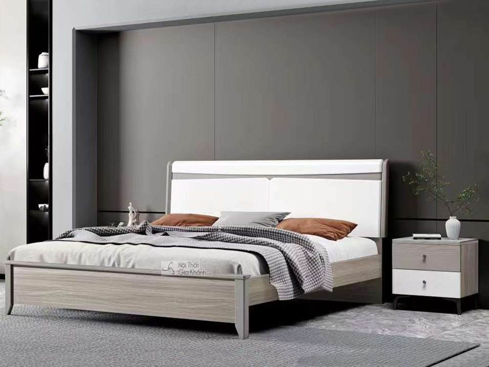 Giường ngủ hiện đại GI2303-1 và tủ đầu giường được chụp từ góc ngang, hơi chếch, làm nổi bật thiết kế tối giản. Giường có…