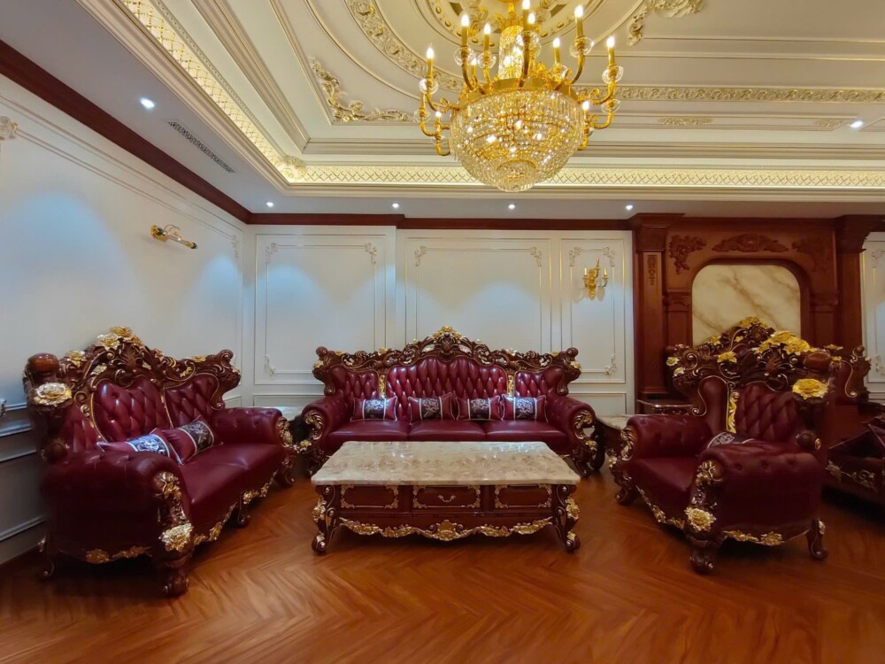 Góc nhìn rộng từ phía trước bộ sofa tân cổ điển SB926-124 trong một phòng khách luxury. Bộ sofa bọc da màu đỏ đô, với các…