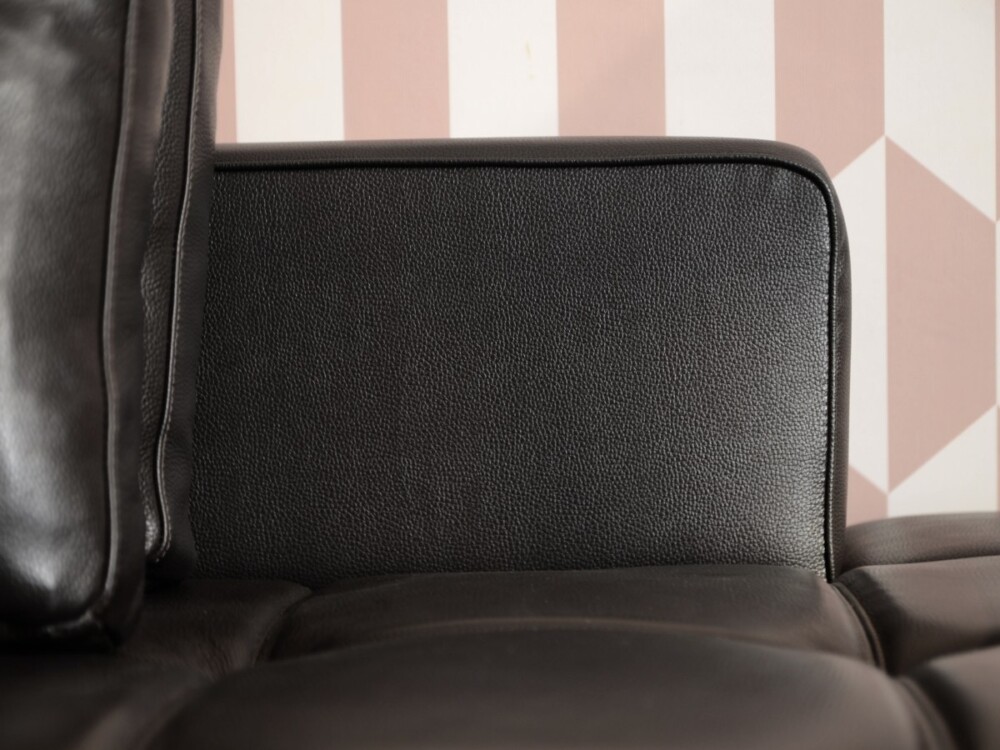 Cận cảnh tựa tay và cạnh bên của sofa SF-HY01. Bề mặt da bò thật màu đen với đường may tinh tế, tạo nên vẻ đẹp gọn gàng. T…