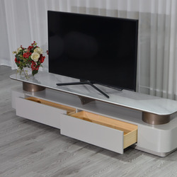Kệ tivi KTKD8630-20 được trưng bày trong một không gian phòng với rèm cửa trắng và sàn gỗ màu xám. Một ngăn kéo của kệ đượ…