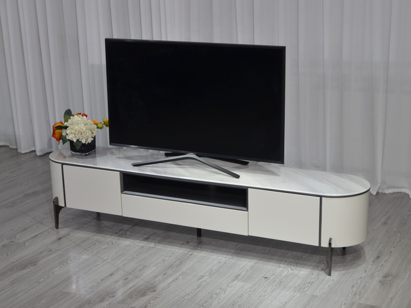 Kệ tivi Verona KTKD9863-20 đặt trong không gian phòng khách đơn giản với rèm trắng. Kệ có mặt đá vân trắng, thân màu kem b…