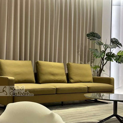 Sofa băng ba chỗ SF2203 màu vàng mù tạt, đặt trong không gian phòng khách hiện đại với rèm cửa màu be và cây xanh trang tr…
