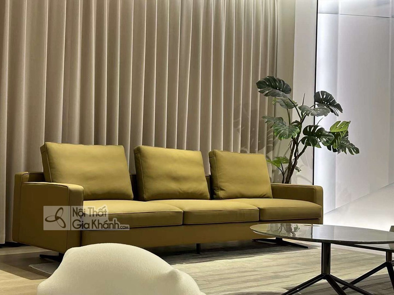 Sofa băng ba chỗ SF2203 màu vàng mù tạt, đặt trong không gian phòng khách hiện đại với rèm cửa màu be và cây xanh trang tr…