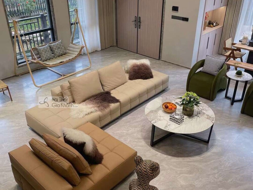 Góc chụp từ trên cao của bộ sofa SF2216, tập trung vào phần băng dài màu be nhạt và đôn/ghế đơn màu nâu da bò, với các gối…