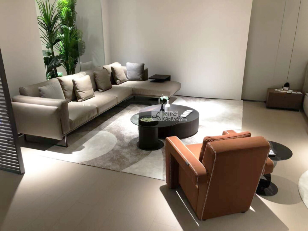 Bộ sofa góc trái SF0064GT màu xám ghi được chụp từ góc nhìn chéo, tập trung vào sự kết hợp giữa sofa và ghế đơn màu nâu ca…