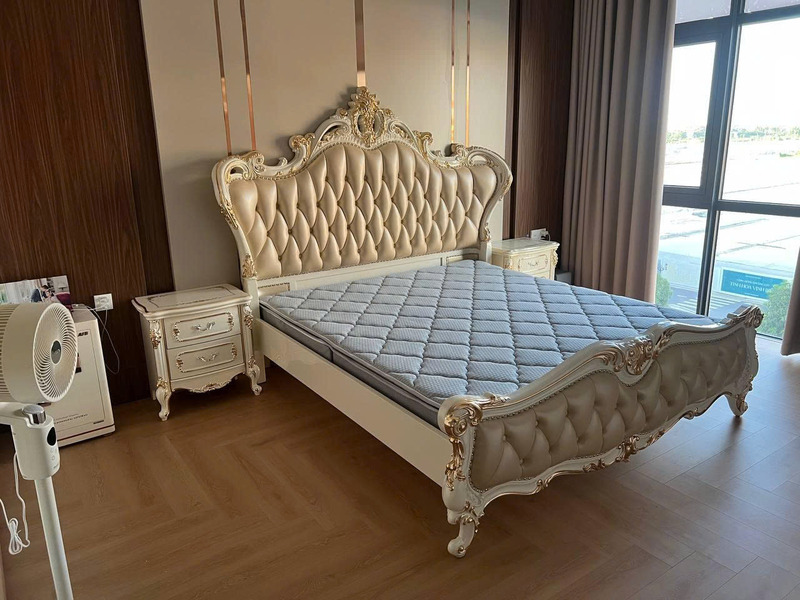Giường ngủ bọc da GIB22-18 đặt trong phòng ngủ thực tế, góc chụp ngang, có nệm nhưng chưa có ga gối. Giường màu trắng ngọc…