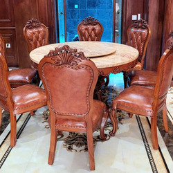 Bộ bàn ăn tròn tân cổ điển với 6 ghế được sắp xếp quanh bàn, chụp từ góc hơi chếch phía trước. Bàn có mặt đá màu vàng kem…