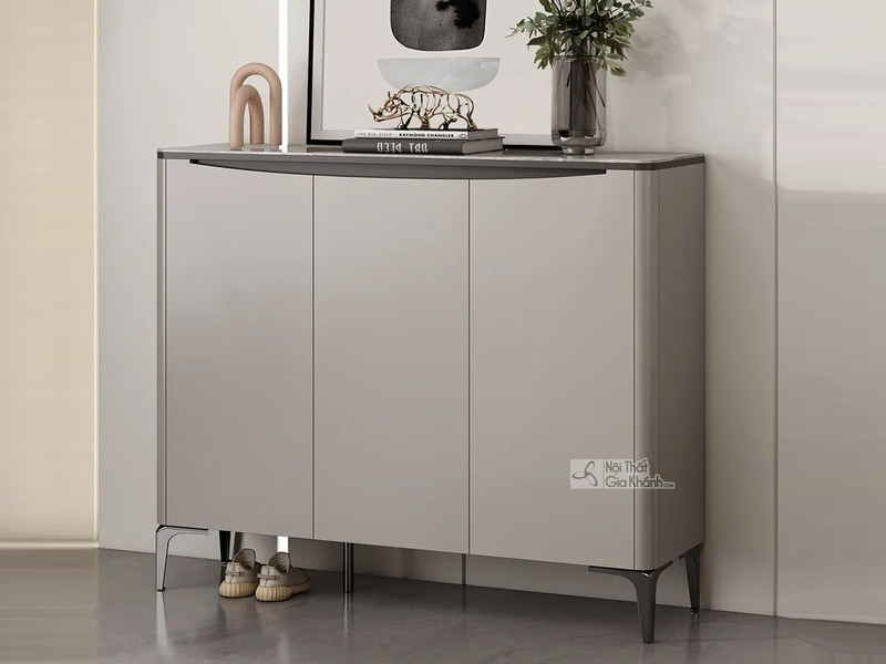 Tủ giày nhập khẩu TD3103 với ba cánh tủ màu ghi nhạt, thiết kế hiện đại, đặt trong không gian tiền sảnh. Mặt tủ có viền mà…