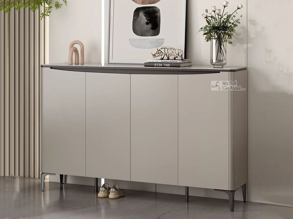 Tủ giày hiện đại TD3105 chụp cận cảnh từ góc thấp, đặt trong không gian tiền sảnh. Tủ có bốn cánh mở màu nâu xám nhạt, mặt…