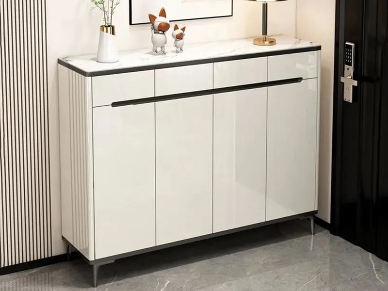 Tủ giầy hiện đại TDHB160 màu trắng bóng, mặt trên ốp đá vân xám, đặt ở lối vào. Tủ có sáu cánh tủ đóng mở và một ngăn kéo…