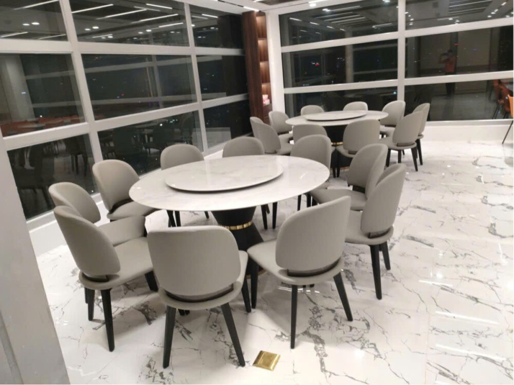 Hình ảnh chụp từ xa, bao quát bộ bàn ăn tròn BA805-Y925 với 8 ghế trong một showroom nội thất rộng lớn, có thể thấy một bộ…