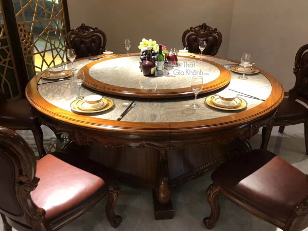 Bàn ăn tròn BA02-22 được bày biện sang trọng với chén đĩa, ly rượu và bình hoa tươi trên mâm xoay. Mặt bàn đá cẩm thạch tự…