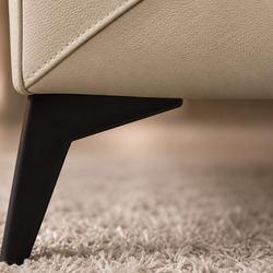 Cận cảnh chân ghế kim loại màu đen của sofa E001-113 da Nano màu kem nhạt, đặt trên thảm trải sàn. Thiết kế chân ghế mảnh…