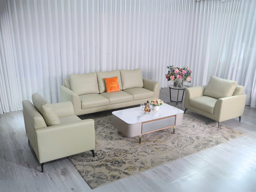 Bộ sofa E001-113 da Nano màu kem nhạt, gồm ghế băng 3, ghế băng 1 và ghế đơn, được bố trí trong không gian phòng khách với…