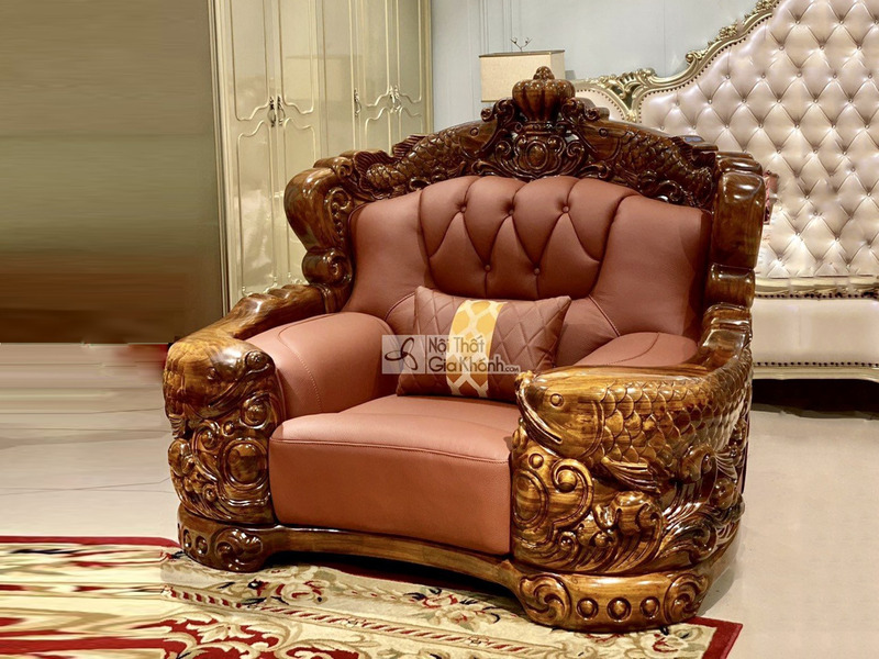 Cận cảnh ghế sofa đơn trong bộ sưu tập, chụp từ góc hơi chếch. Ghế có khung gỗ mun Nam Phi chạm khắc hình cá chép và hoa v…