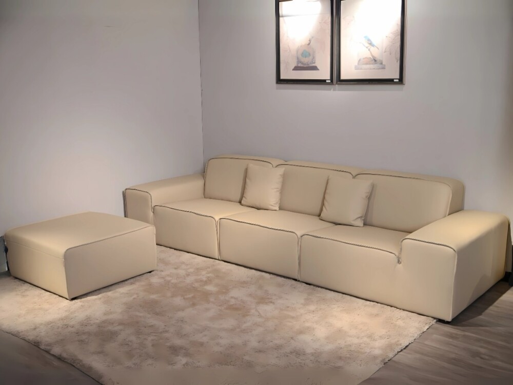Sofa băng SFA38-32 màu kem nhạt bọc da bò 100% và đôn rời, đặt trên thảm lông trong không gian phòng khách tối giản. Thiết…