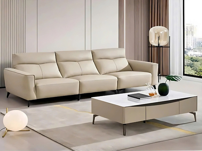 Sofa băng SF8137 màu kem nhạt, bọc da bò thật, được chụp ở góc ngang trong không gian phòng khách hiện đại. Sofa có ba chỗ…