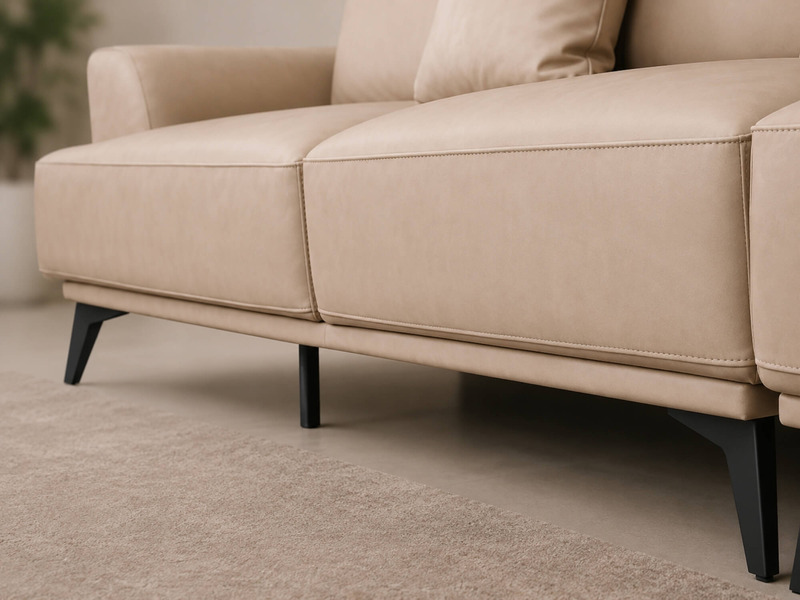 Cận cảnh phần chân và gầm của sofa da AURELIA màu be nhạt. Chân sofa kim loại màu đen thiết kế mảnh, tạo khoảng trống dưới…