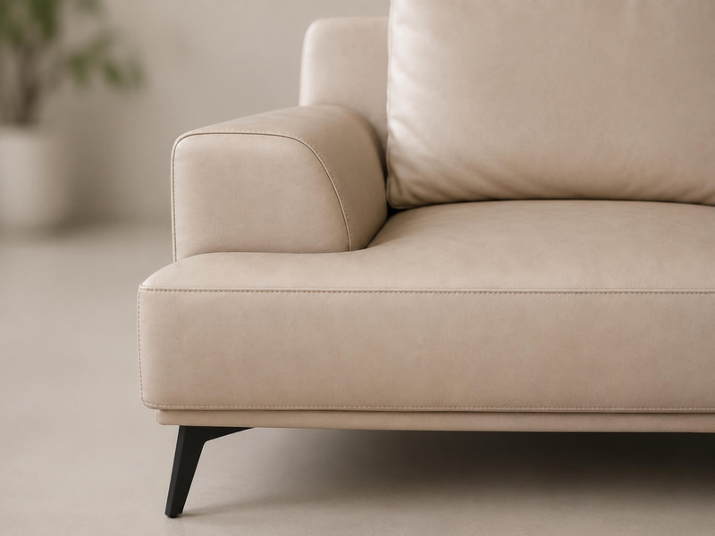 Chi tiết tay vịn và phần đệm ngồi của sofa da AURELIA màu be nhạt, chụp cận cảnh. Bề mặt da Lex nhân tạo mềm mại, đường ma…