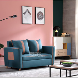 Sofa giường gấp SF1012B-3 màu xanh đậm với các đường viền và chi tiết túi trang trí màu hồng đất, đặt trong không gian phò…